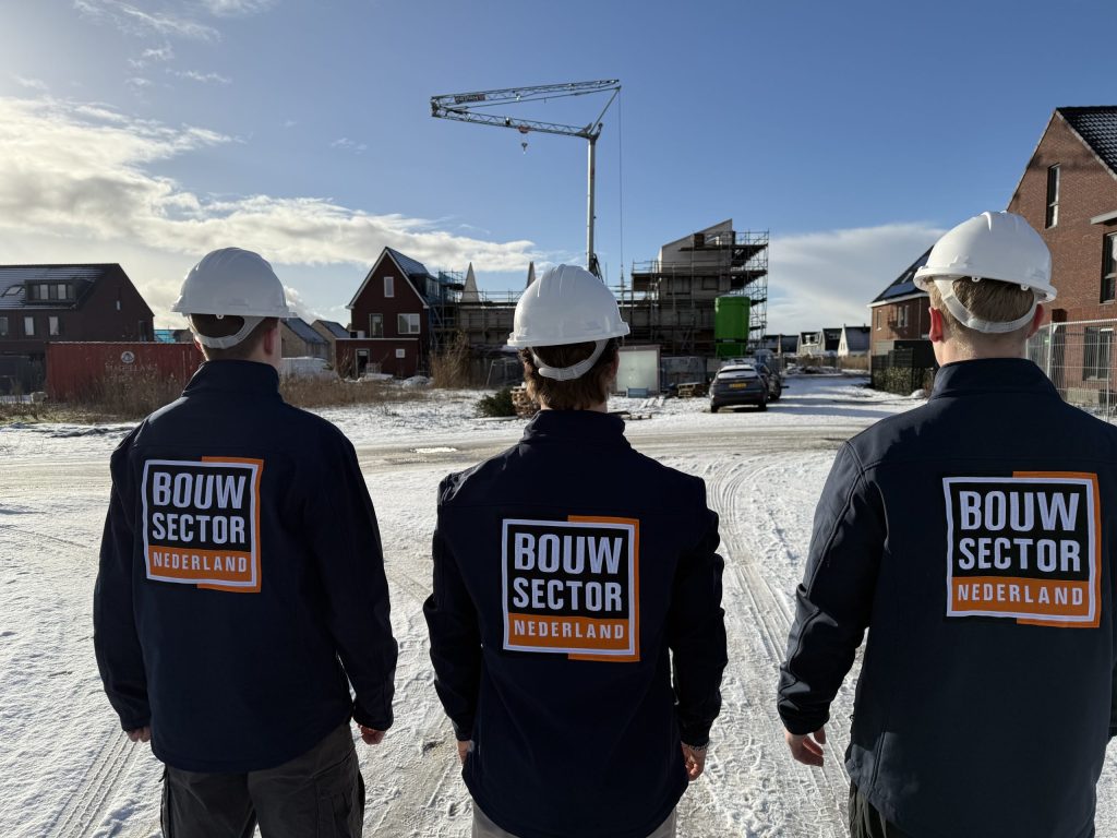 Vakmensen van Bouwsector Nederland met witte helm op een besneeuwde straat met bakstenen nieuwbouw